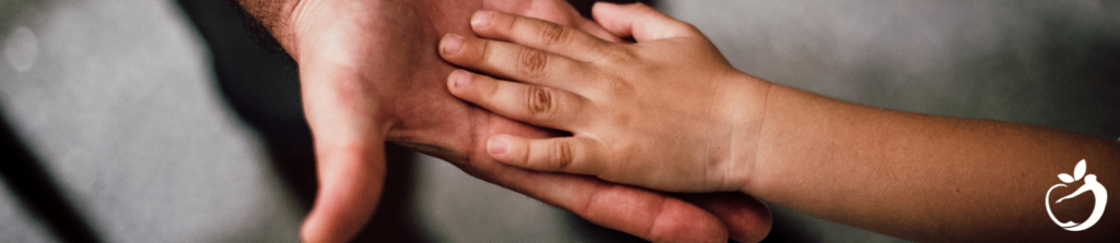 child's hand on top of an adults hand