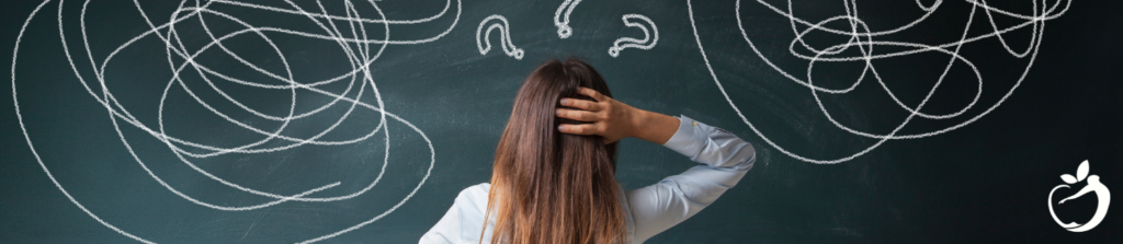 woman standing in front of a chalkboard with a bunch of scribbles and question marks on it