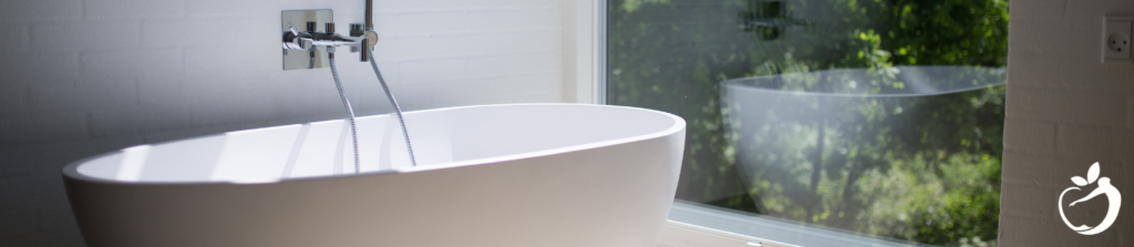 a large white bathtub next to a large window with an outdoor view