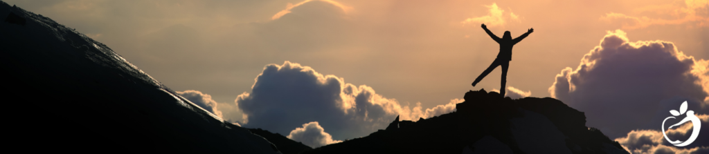 person doing yoga at the top of a mountain at sunset