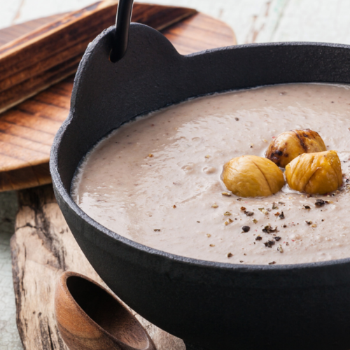 Recipe Post Header Image - Chestnut Soup With Cauliflower. Image of soup in a bowl garnished with roasted chestnuts.