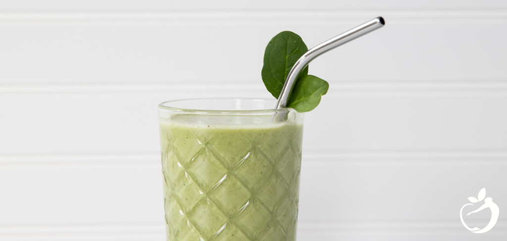 green lunchtime smoothie in a glass with a straw