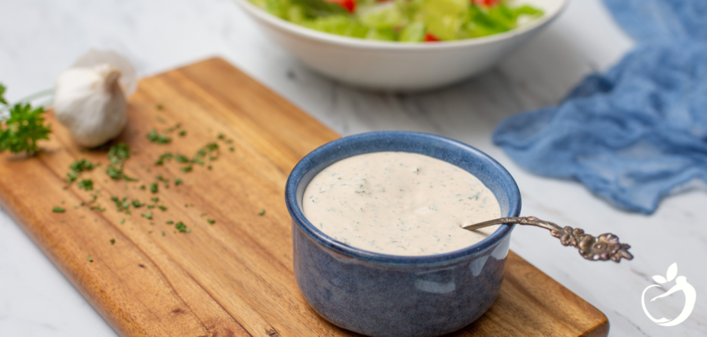 Recipe Post Header Image - Paleo Ranch Dressing. Image of dressing in a cup with a spoon.
