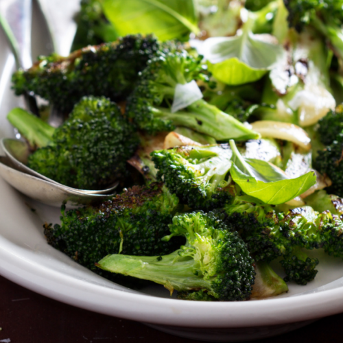Showing an image of roasted broccoli with lemon and basil dressing on a plate.