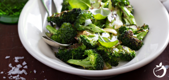 Showing an image of roasted broccoli with lemon and basil dressing on a plate.