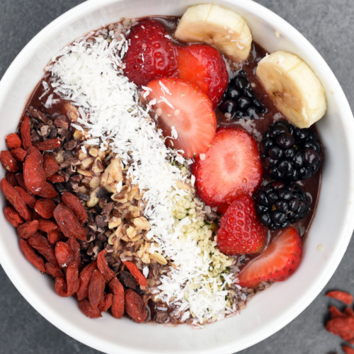 Recipe Post Header Image of Toasted Coconut Cereal in a bowl with fresh berries and shredded coconut.