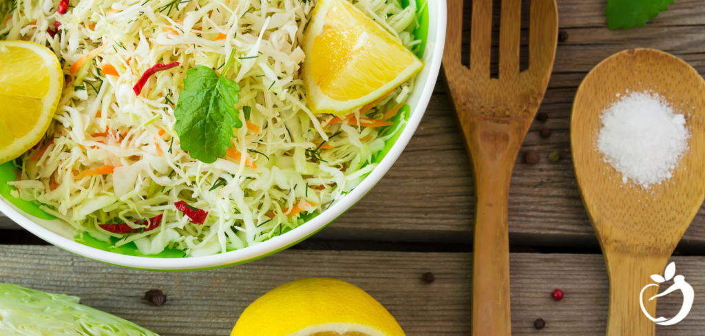 winter salad with lemon and mint in a white bowl with wooden spoons next to it